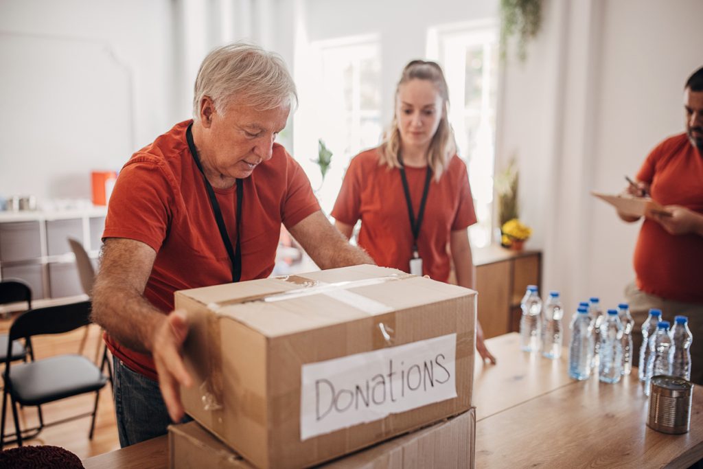 Elderly man packing a box marked for donations