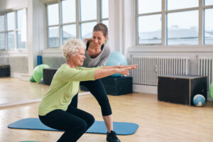 fitness coach helping an elderly woman exercise