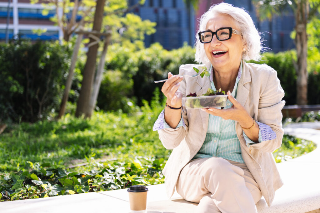 happy senior lady eating a salad outside on a sunny day